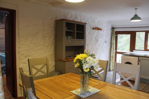 a dining room with a table with a vase of flowers at Ghyll Burn Cottage and Barn End Cottage in Alston