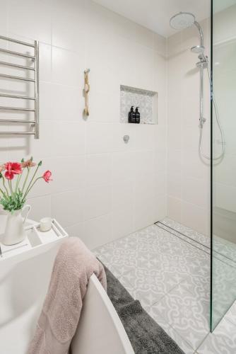 a white bathroom with a tub and a shower at Battery Hill Pet-Friendly Poolside Paradise in Caloundra