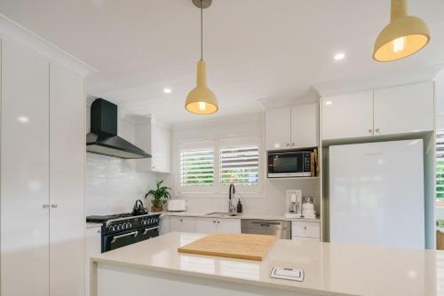 a kitchen with white cabinets and a white counter top at Battery Hill Pet-Friendly Poolside Paradise in Caloundra