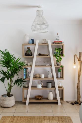 a ladder shelf in a living room with a plant at Battery Hill Pet-Friendly Poolside Paradise in Caloundra