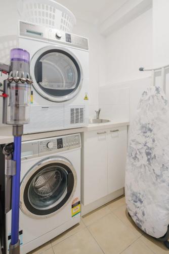 a kitchen with a washing machine and a sink at Battery Hill Pet-Friendly Poolside Paradise in Caloundra
