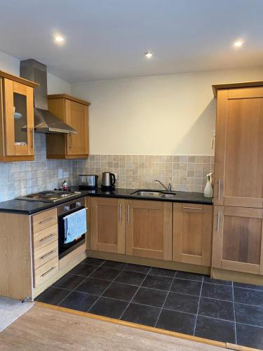 a kitchen with wooden cabinets and black tile floors at CamdenWharf in Cork