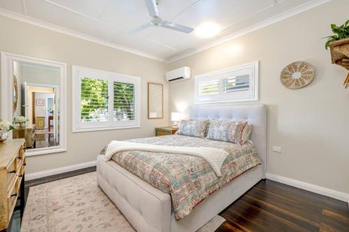 a bedroom with a bed and two windows at Cathy's Cottage in Cairns