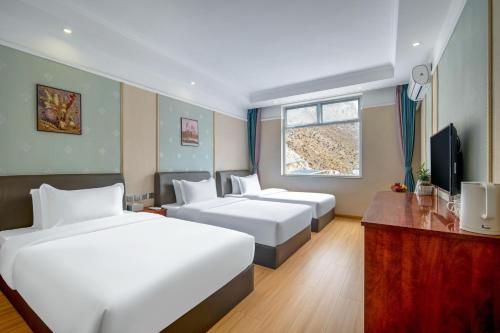 pokój hotelowy z 2 łóżkami i telewizorem w obiekcie Jiuzhai Journey Hotel w mieście Jiuzhaigou