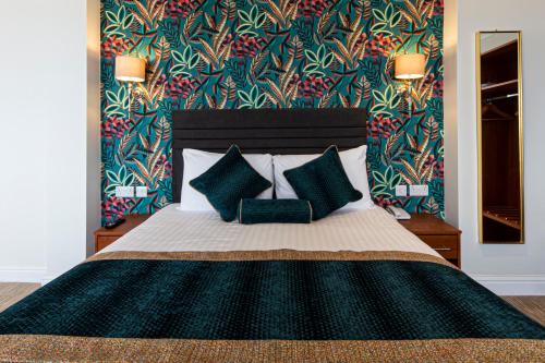 a bedroom with a large bed with blue pillows at The Beaches Hotel and Spa in Prestatyn