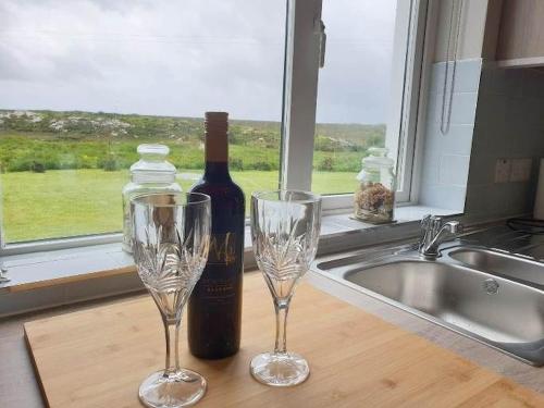 una botella de vino y dos copas de vino en una barra de cocina en Hillside House, en Ballinaboy
