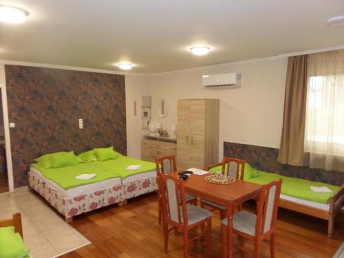 Habitación con 2 camas, mesa y sillas en Karneol Apartmanház Cserkeszőlő, en Cserkeszőlő