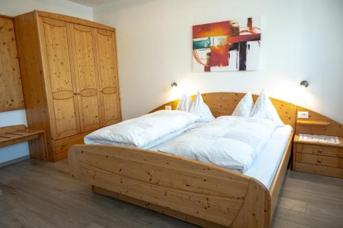 a bedroom with a wooden bed with white pillows at Garni Meinrad in Ora/Auer