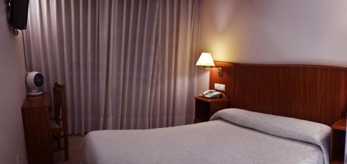 um quarto de hotel com uma cama e um telefone ao lado de uma janela em HOTEL LORENZO em Carvalhinho