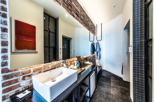 a bathroom with a white sink and a brick wall at H Avenue Hotel Gwangalli branch in Busan