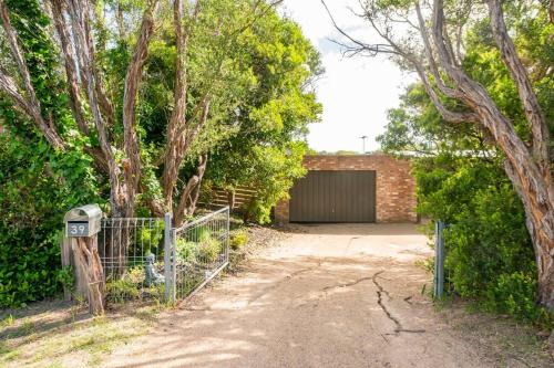 a garage with a gate and a fence and trees at Coastal cottage, perfectly positioned in Tootgarook