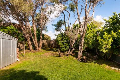 a yard with a fence and trees and grass at Coastal cottage, perfectly positioned in Tootgarook