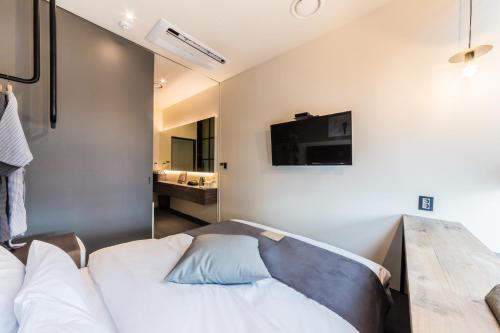 a bedroom with a bed and a tv on the wall at H Avenue Hotel Gwangalli branch in Busan