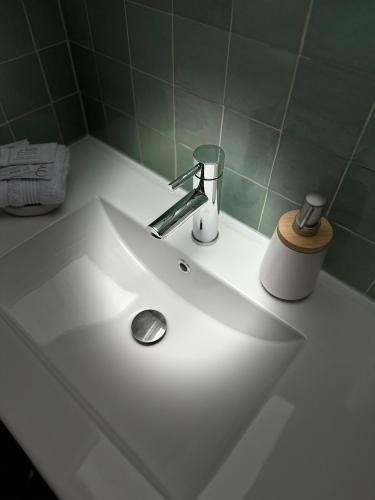 La salle de bains est pourvue d'un lavabo blanc et de carrelage vert. dans l'établissement Cosy Apartment in City Center, à Honfleur