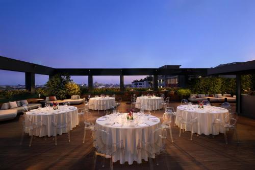 a room with white tables and chairs with a blue screen at The Westin Palace, Milan in Milan