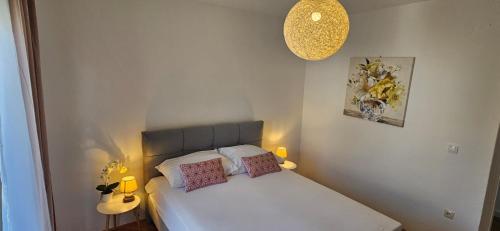 a small bedroom with a white bed with two pillows at Apartman Mia with pool1 in Split