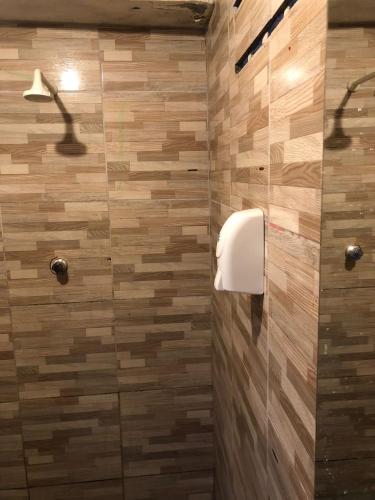 La salle de bains est pourvue d'une douche et de carrelage en bois. dans l'établissement Hostel Vegaspub1600 Experiência, à Campina Grande