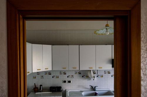 cocina con armarios blancos, lavabo y espejo en Flyway en Nápoles