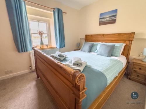 a bedroom with a wooden bed with blue curtains at Dolphin Cottage Chesil Beach in Portland