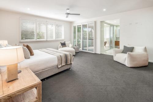 a bedroom with a bed and a couch and chairs at Headlands Hideaway - Pet Friendly Home at Moffs in Caloundra