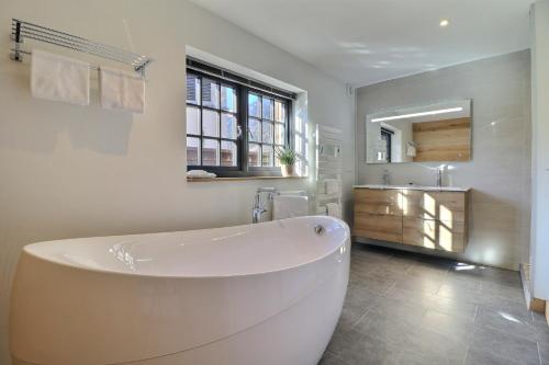 uma banheira branca na casa de banho com um lavatório em Chalet de standing avec sauna em Saint-Jean-dʼAulps