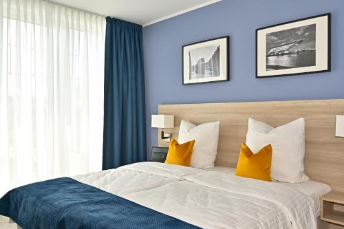 a bedroom with a bed with blue walls and yellow pillows at HotelHafenWedel in Wedel