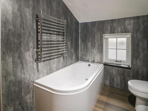 a bathroom with a white tub and a toilet at Church How Cottage in Seascale