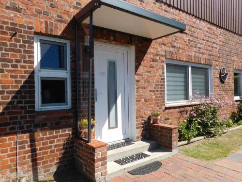 a brick house with a white door and windows at Fewo Storchennest in Kollmar