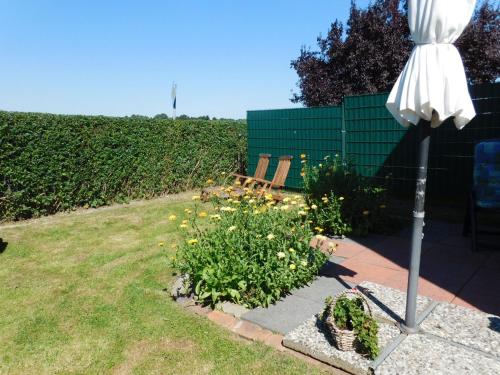 a garden with a bench and an umbrella and flowers at Fewo Storchennest in Kollmar