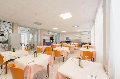 a dining room with white tables and orange chairs at Hotel Santa Faz in Benidorm