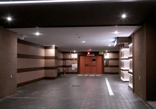 an empty hallway of a building with a red door at M'z HOTEL in Nagoya