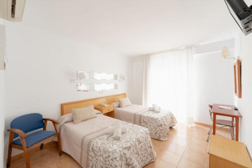 a room with two beds and a chair and a table at Hotel Santa Faz in Benidorm
