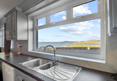 a kitchen with a sink and a large window at Glassillaun Beach House in Renvyle