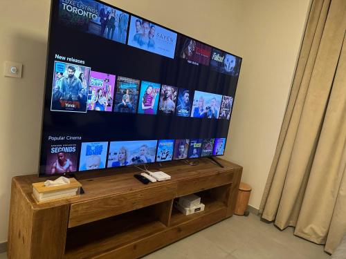 a flat screen tv sitting on top of a wooden stand at WelcomeHome Apartments Aljada in Sharjah