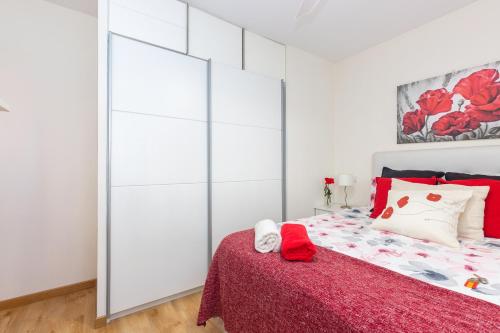 um quarto branco com uma cama com um cobertor vermelho em Apartamento Puente de Segovia em Madri