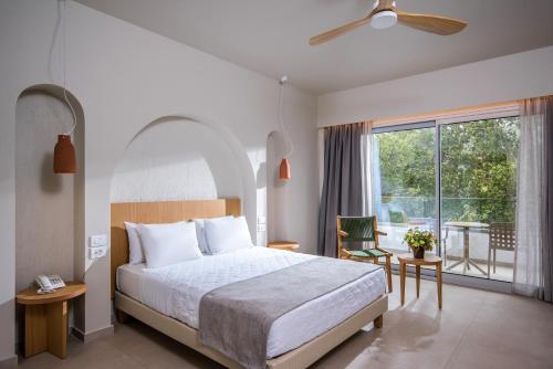 een slaapkamer met een bed en een groot raam bij South Coast in Makry Gialos