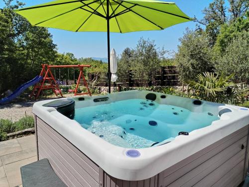 a hot tub with an umbrella next to a playground at The Forest House Krk 2 in Kras