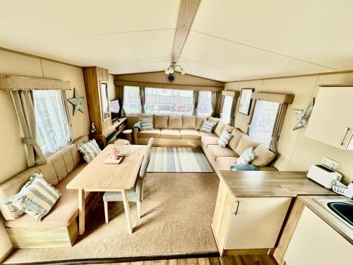 Everton的住宿－Coastal Retreat a gorgeous 3 bedroom Caravan B46，客厅配有沙发和大篷车内的桌子