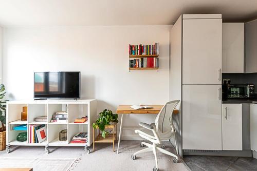 eine Küche mit einem Schreibtisch und einem weißen Kühlschrank in der Unterkunft Urban and Stylish Apartment in London