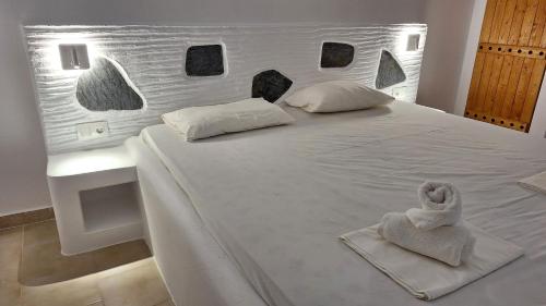 Una cama blanca con toallas encima. en Chryssa Bungalows, en Ándros