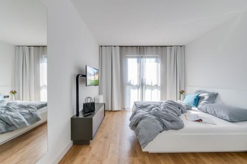 a white bedroom with a bed and a television at SMARTments business Berlin Karlshorst in Berlin
