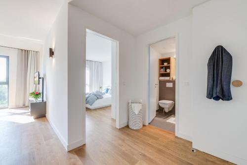 Habitación blanca con espejo y dormitorio en SMARTments business Berlin Karlshorst en Berlín
