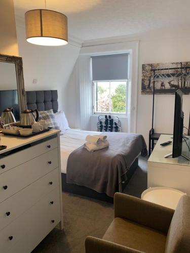 a bedroom with a bed and a dresser with a mirror at Ellwyn House in Edinburgh