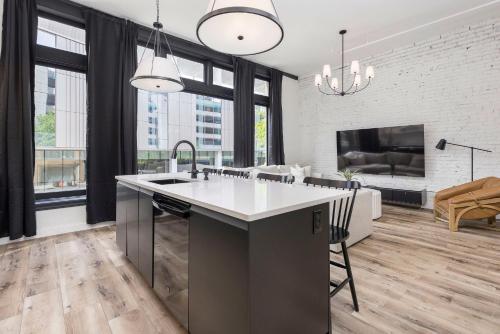 a kitchen with a sink and a living room at Decadent Cityscape Retreat in Louisville