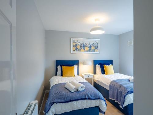 a bedroom with two beds with blue and yellow pillows at Eve's Townhouse in Clifden