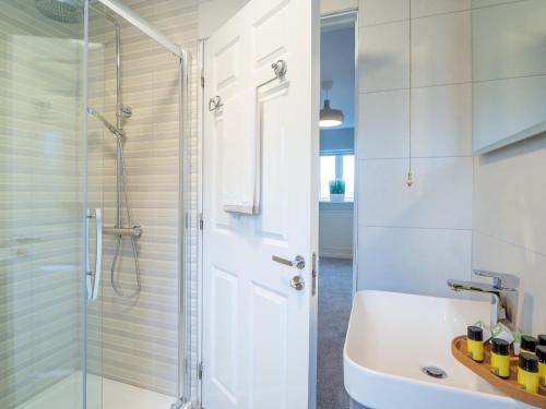 a white bathroom with a shower and a sink at Eve's Townhouse in Clifden