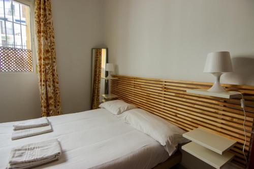 sypialnia z białym łóżkiem z drewnianym zagłówkiem w obiekcie RentalSevilla Apartamento encantador en el Gran Poder w Sewilli