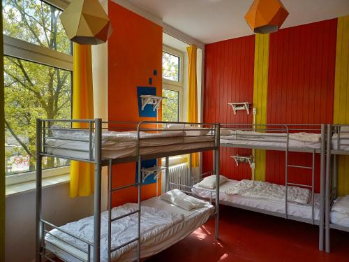 instantSleep Backpackerhostel St Pauli في هامبورغ: ثلاثة أسرة بطابقين في غرفة مع جدران ملونة