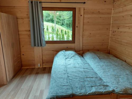 a bed in a wooden room with a window at Willa Ozark in Zawóz