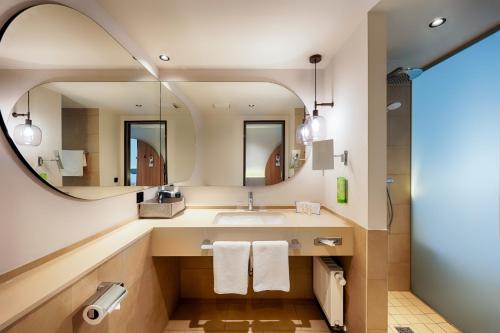 a bathroom with a sink and a mirror at Welcome Hotel Darmstadt City Center in Darmstadt